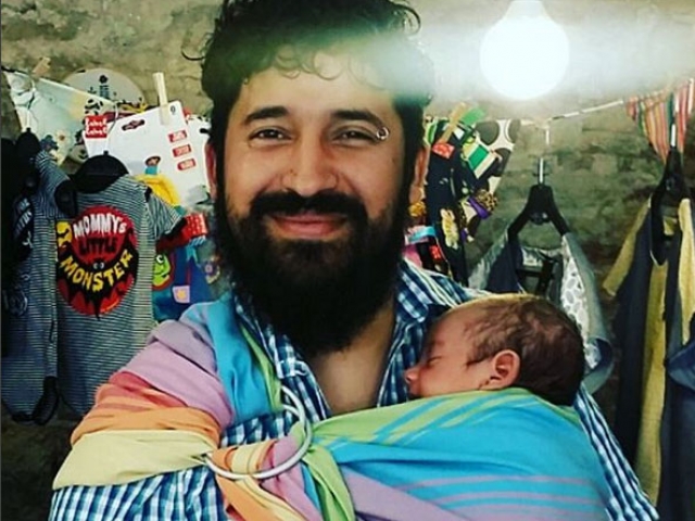 Padre con bandolera portabebes de anilla llevando a su bebe